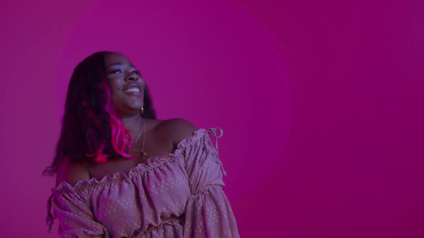 A woman is sitting indoors and is smiling and laughing