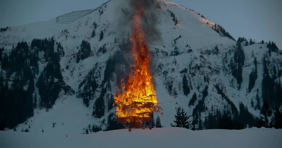 A tree is in flames on a snow covered mountain side