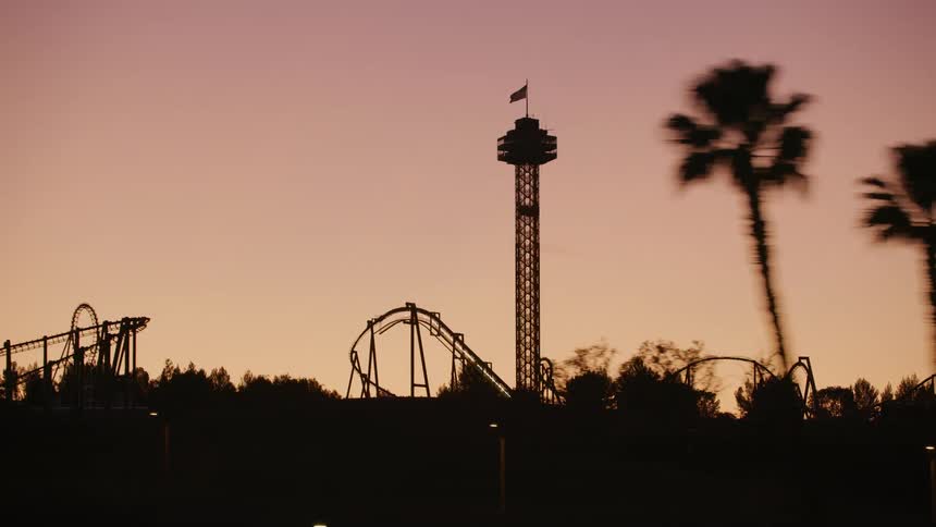 An american flag flies on top of a ride at an amusement park