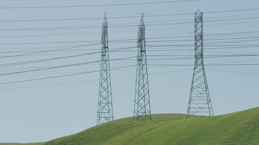 Transmission towers atop a hill in the countryside during the day