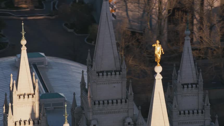 A gold statue of a man sits atop a spire on a historical building
