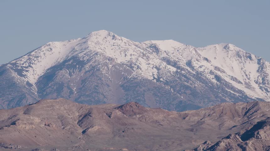 A mountain ridge with snow covered mountains in the distance