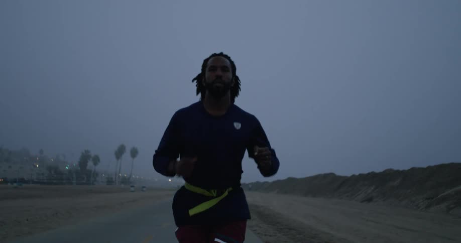Man jogs down road with fog covered town in the background