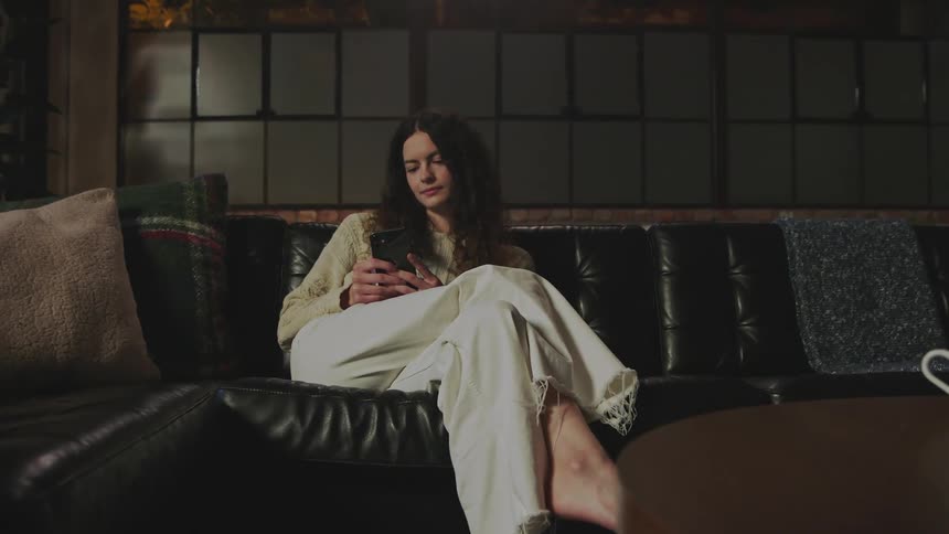 A woman is using her cell phone on the couch