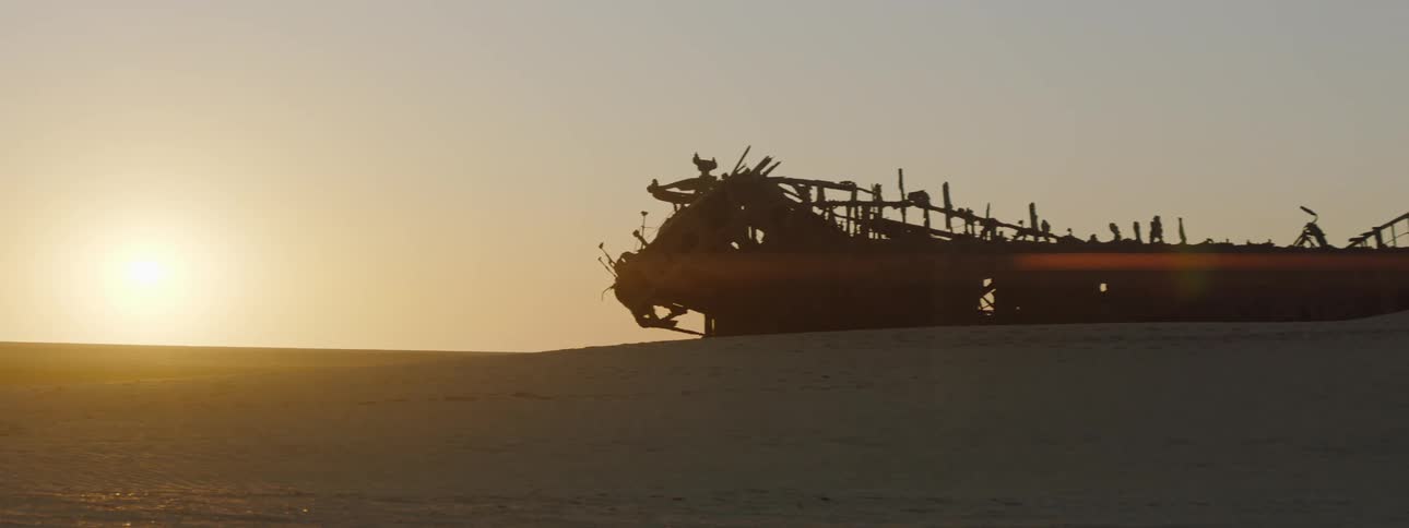A shipwreck in the sand at sunset