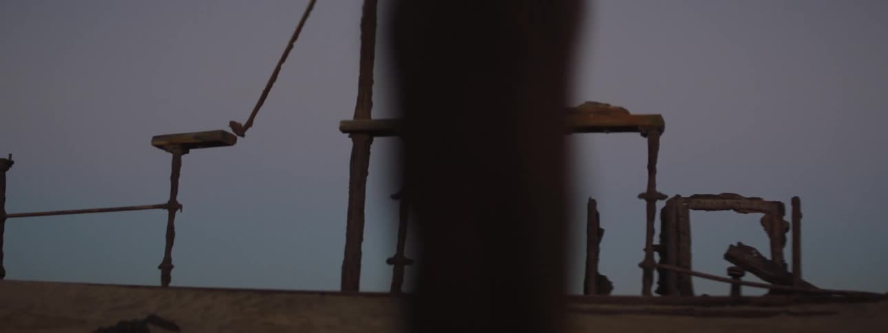 Wreckage sits on a beach under a clear sky