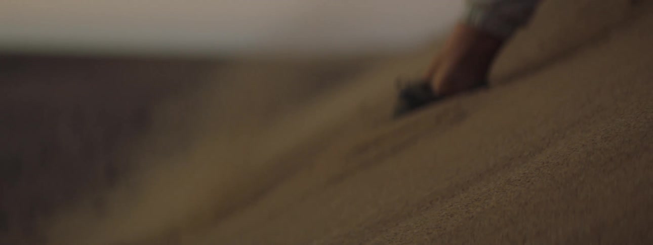 Feet sink into the sand dune as they jog up the slope