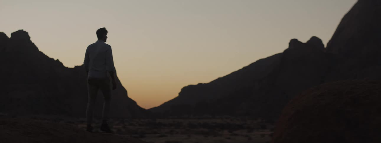 Young man in the desert at sunset