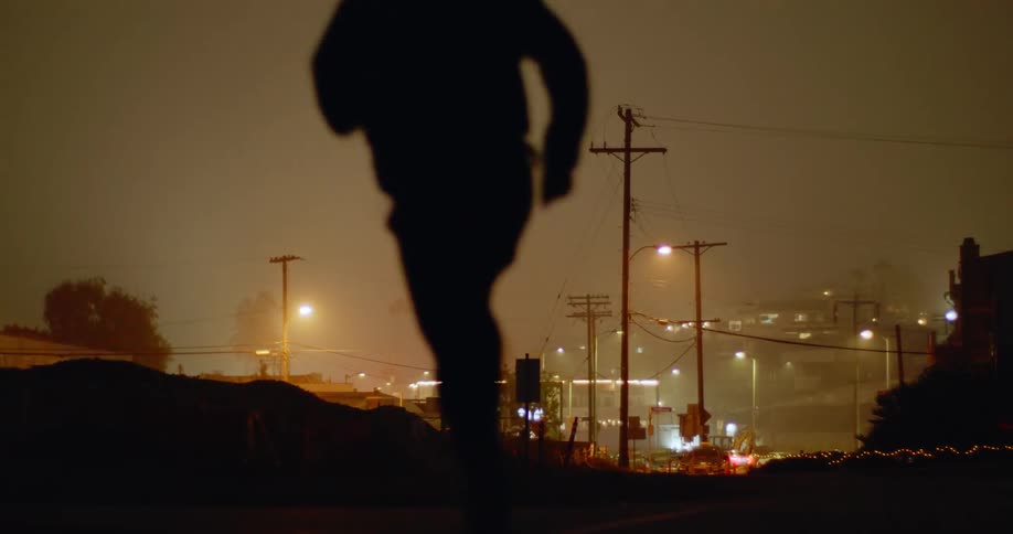 A man jogs up a hilly neighborhood