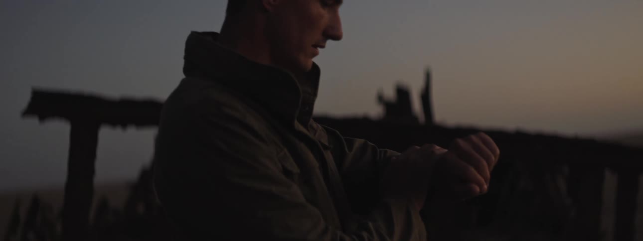 A man checks his watch at sunset