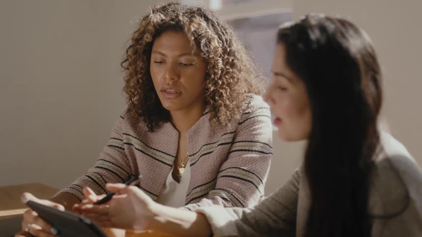 Two women in an office meeting looking at a tablet