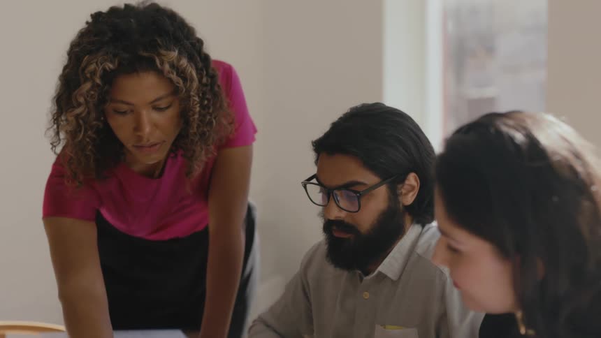 Coworkers sitting at a table in a conference room reviewing documents