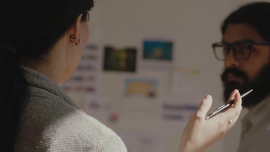 Two workers discuss information displayed on wall