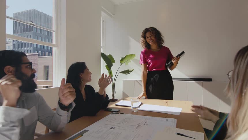 Colleagues congratulate coworker as she walks into the office