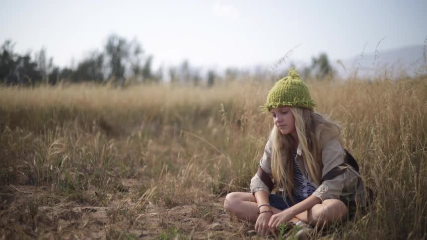A girl is sitting in some grass