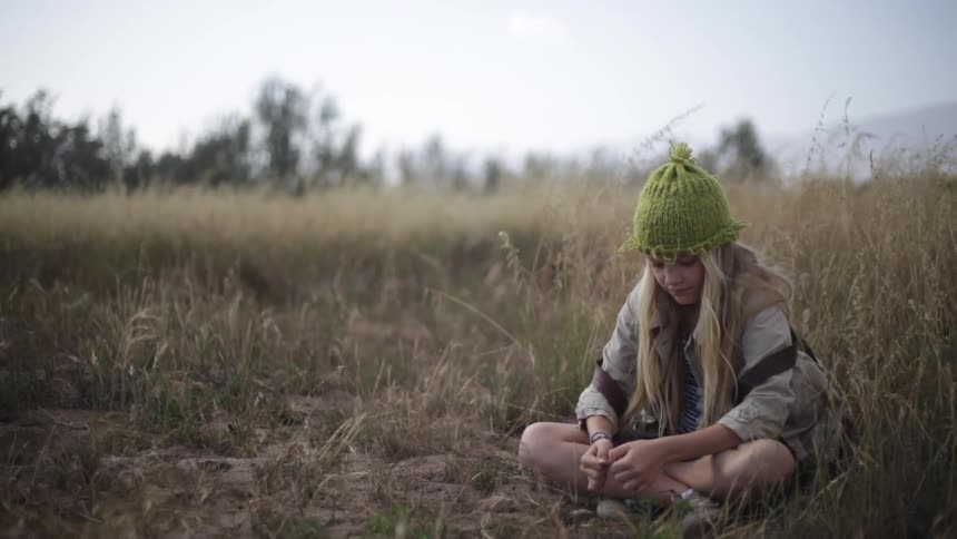 A girl sits on the grass pulling weeds