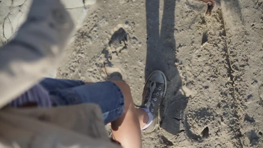 A girl is driving a stick into sand