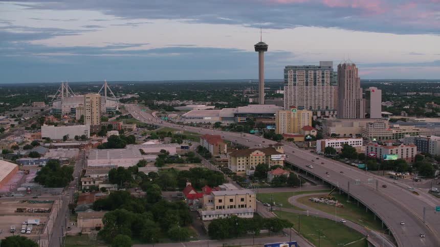 Cars are driving on a highway in a downtown city at dusk