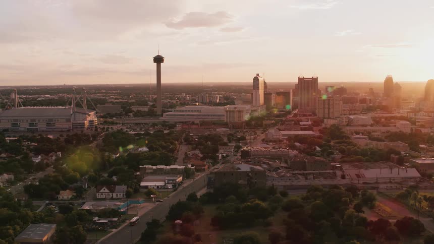 A large city park sits near a stadium in a sprawling downtown