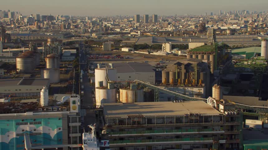 Factories and warehouses border waterfront with downtown skyscrapers in the background