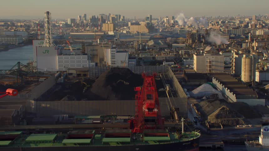 Ships sit near loading dock with city skyline sitting in the background