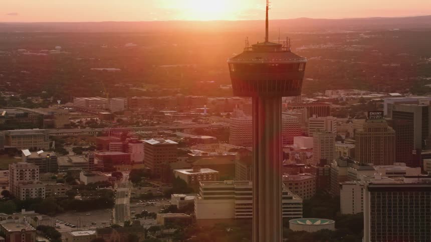 Space needle stands in town stretching to the sun on the horizon under a red sky