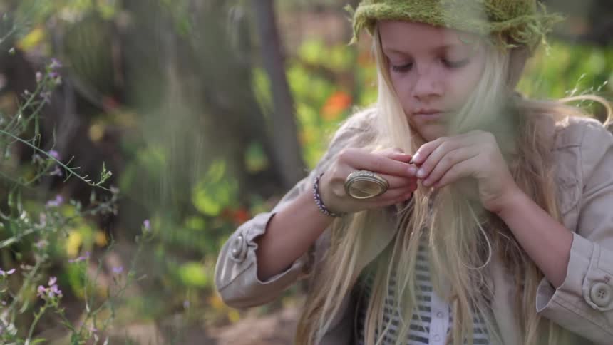 A girl in a green hat puts on a necklace
