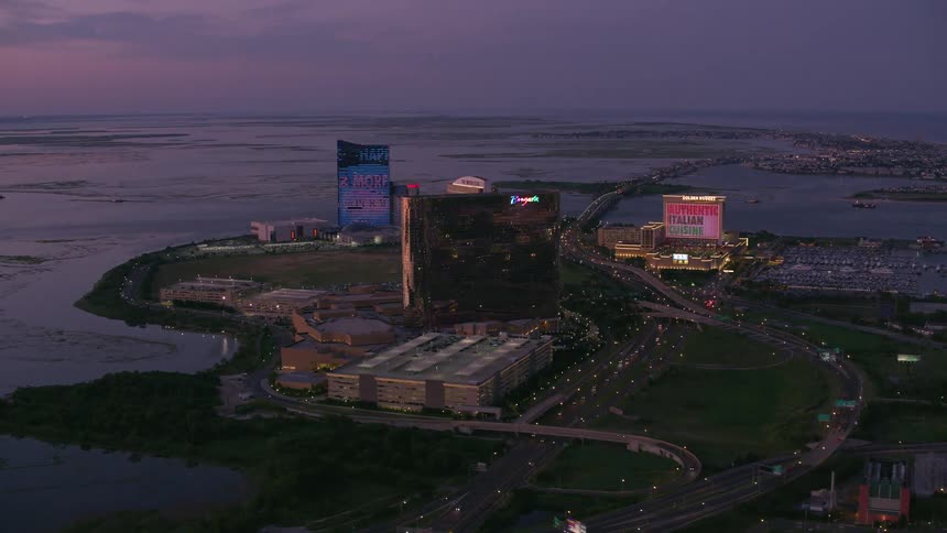 Traffic flows past buildings sitting near the shore as the building sides play images