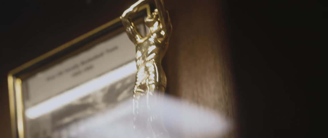 Metallic gold basketball trophy and photograph sit against wood paneling
