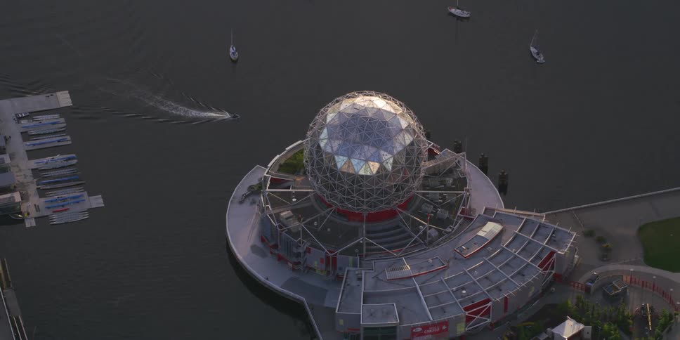 Boats sail near an art installation featuring a large silver sphere