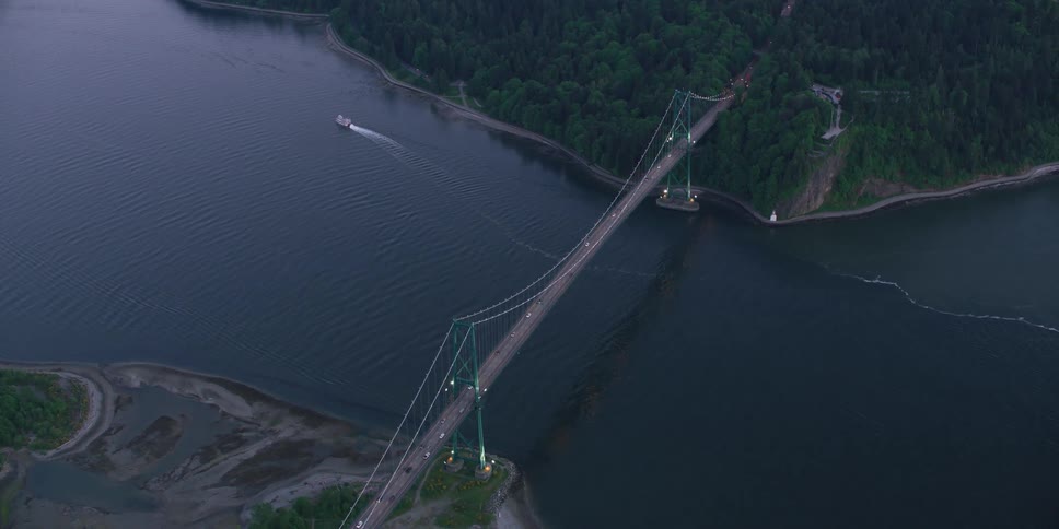 Aerial view of traffic crossing a suspension bridge and a boat sailing in the water
