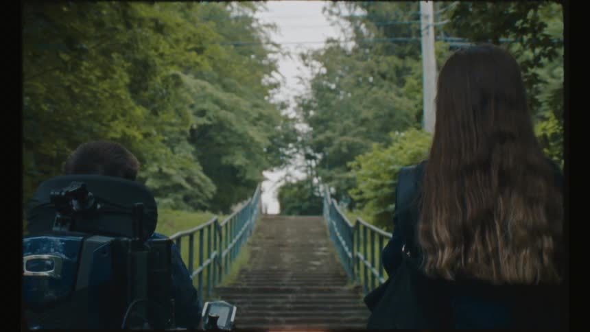 A woman and man in a wheelchair are at the bottom of a staircase