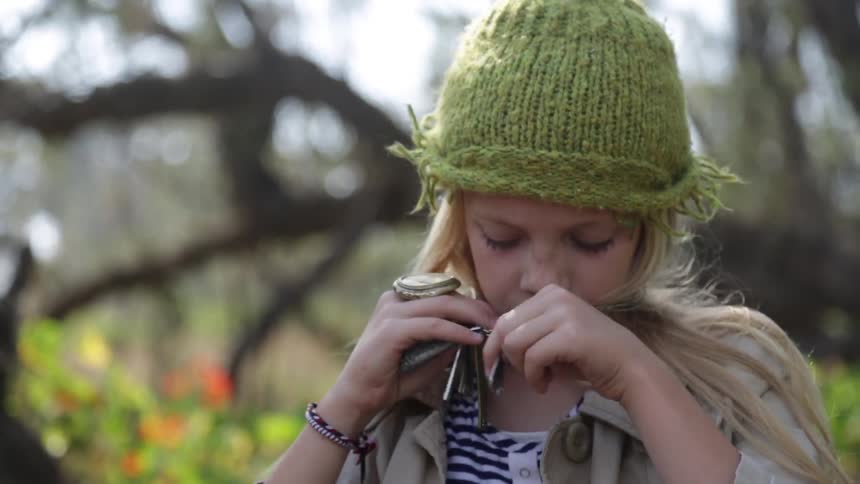 A girl looks through a bag removing a necklace and wearing it