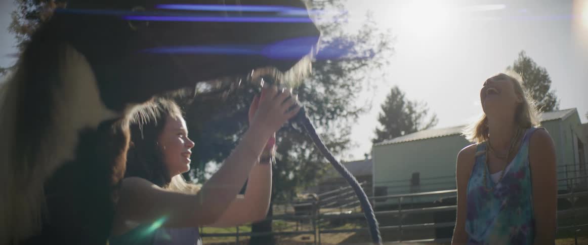Two girls laugh while a horse moves