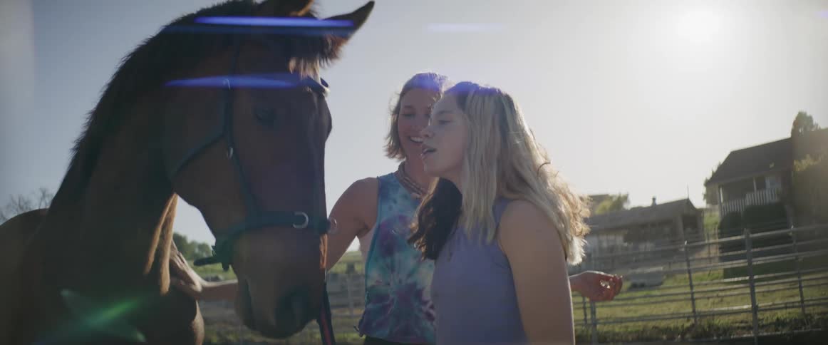 A woman and her daughter pet a horse on their ranch