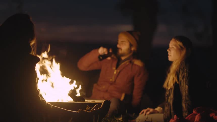 Woman talking while hanging out with friends around a bonfire at night