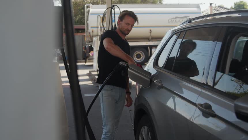 A man is filling up his car with gas during the spring