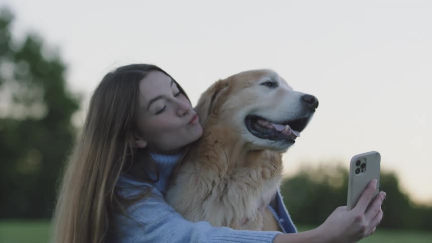 A happy girl takes a selfie with her dog outdoors and laughs
