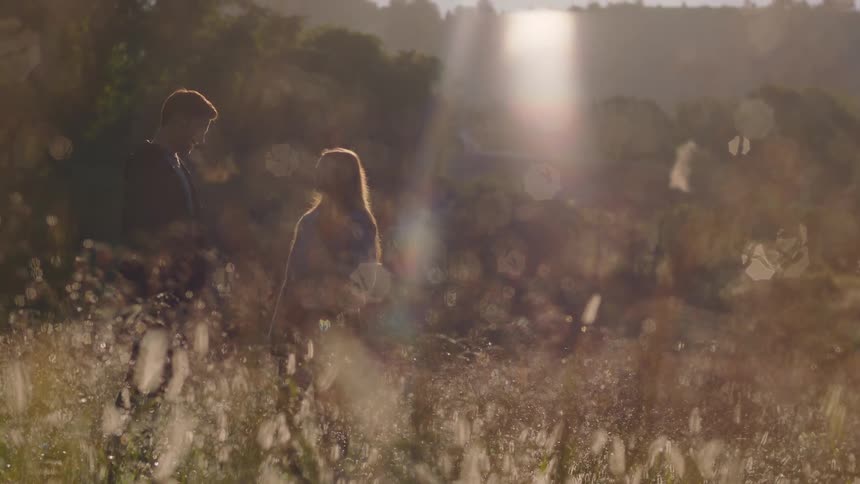 A couple stand in the tall grass together