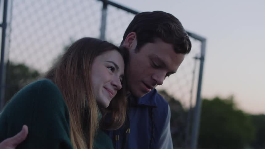 A young couple cuddle outside