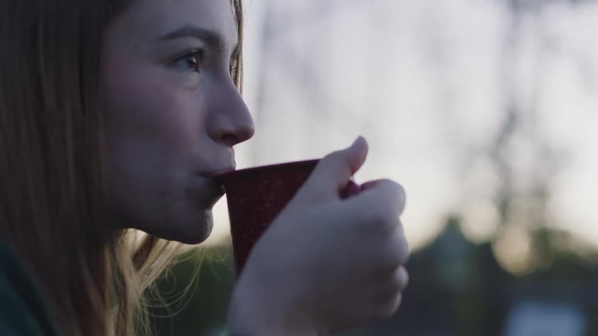 A young woman enjoys coffee outside with her partner