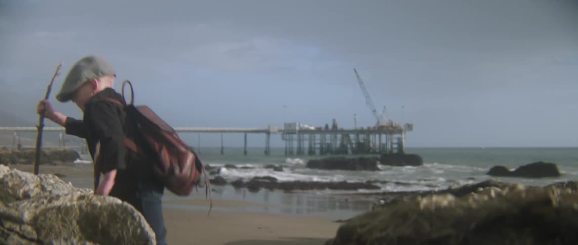 A boy climbs up some rocks on the beach