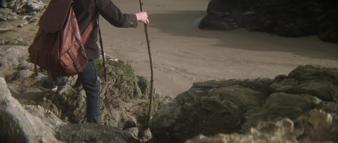 A boy climbs down some rocks