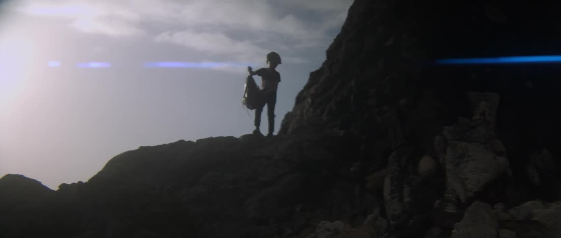 A child throws clothing and his backpack from the top of a cliff