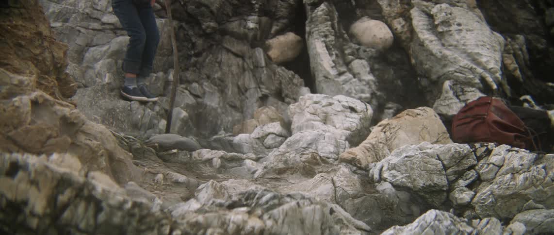 A boy climbs down some rocks
