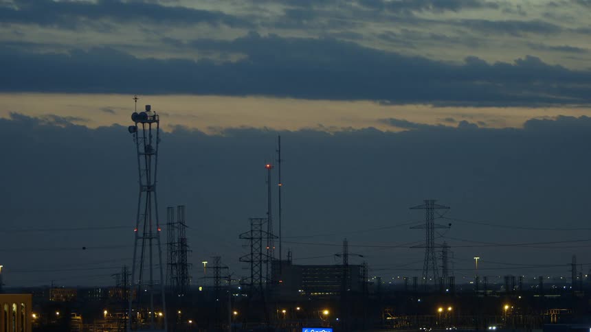 Lights blink on power lines and structures in the city at night