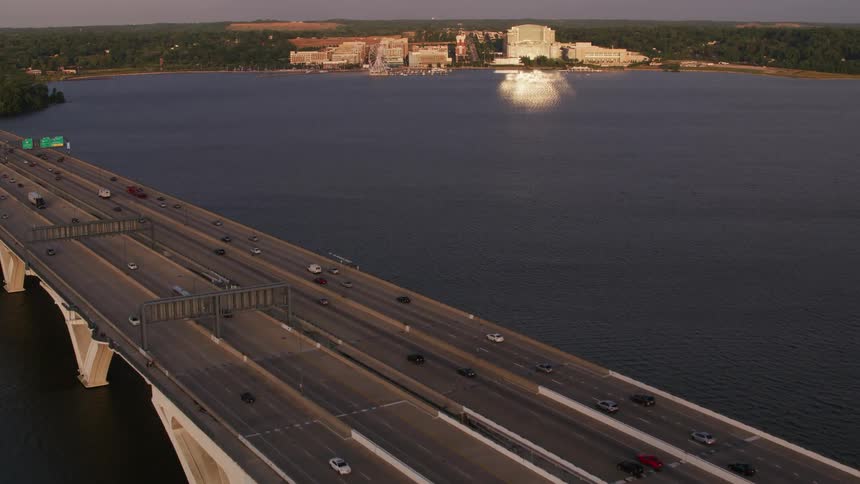 Cars are driving on a bridge over a body of water at dusk