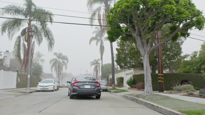 A sedan leaves from being parked in front of a house