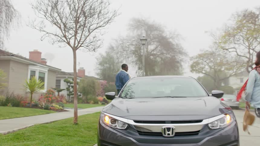 Young couple carrying a picnic basket board a car parked in front of their home