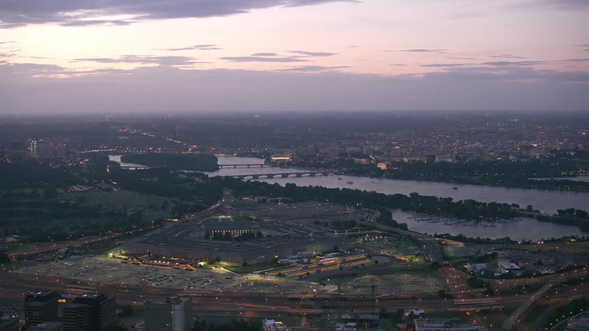 A pentagon shaped government building between a river and a freeway in the evening